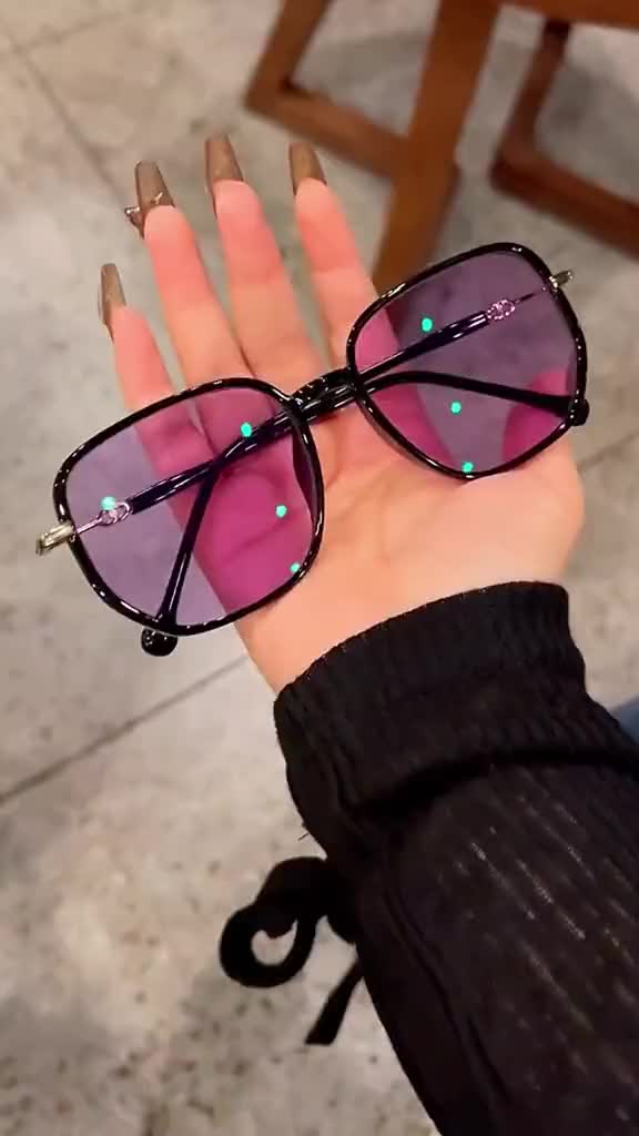 This may contain: a woman's hand holding up two pairs of pink and black sunglasses with diamonds on them