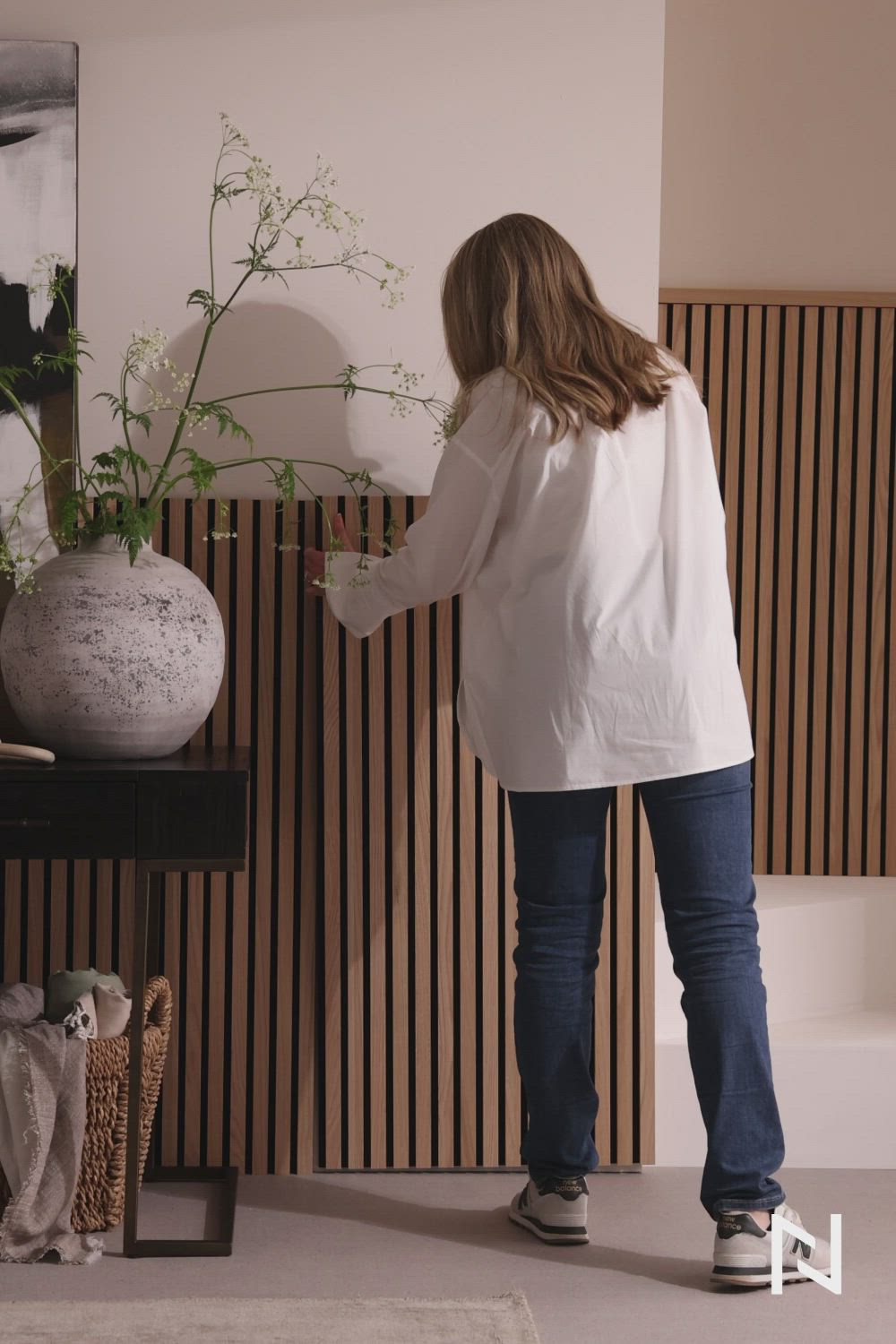 This may contain: a woman standing in front of a vase with flowers