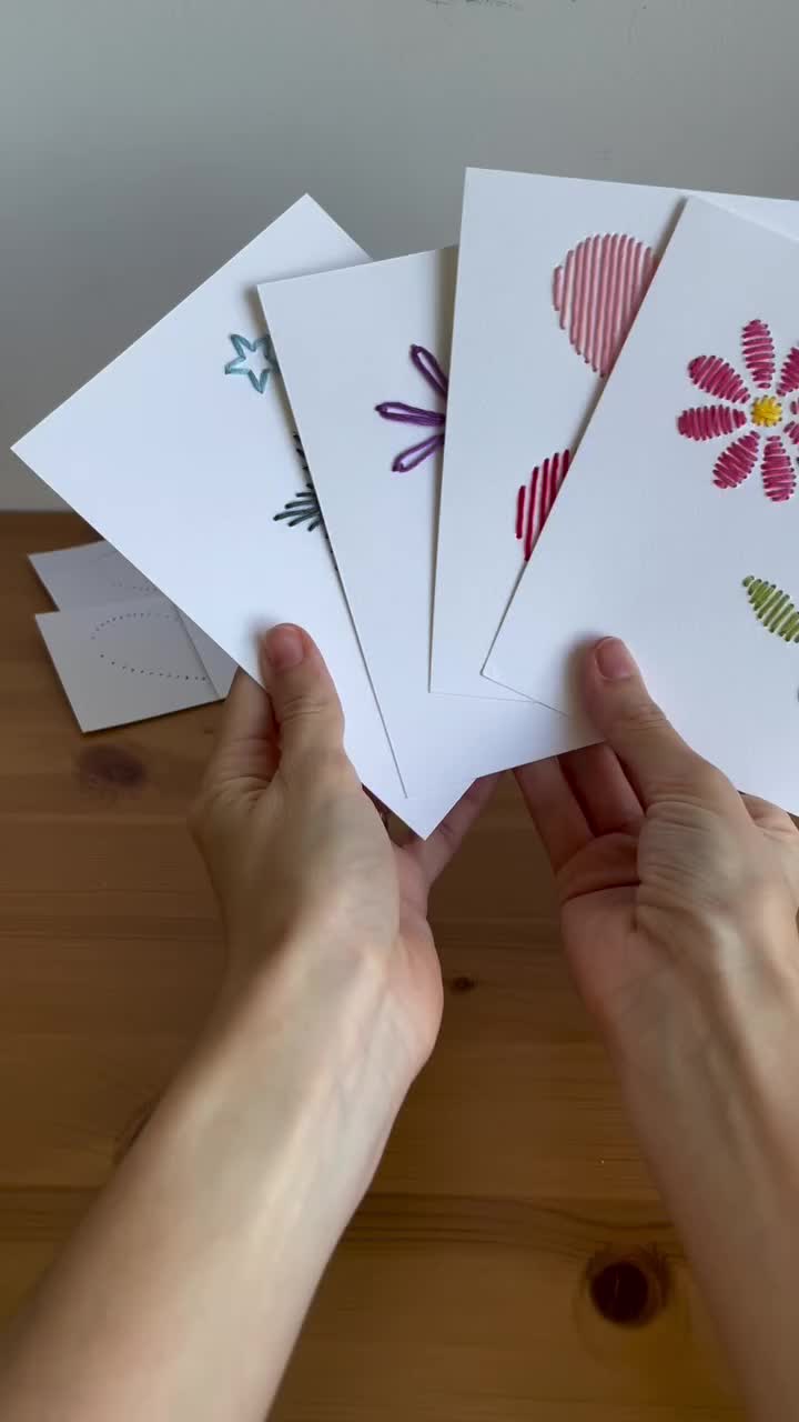 This may contain: hand holding four cards with the words creating paper embroidery on them