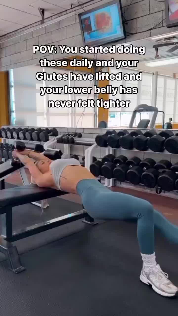 This may contain: a woman laying on top of a bench in a gym with dumbbells behind her