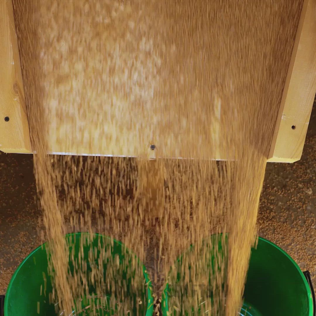 This may contain: a person standing over three green buckets filled with dirt and sand, while the floor is covered in wood planks