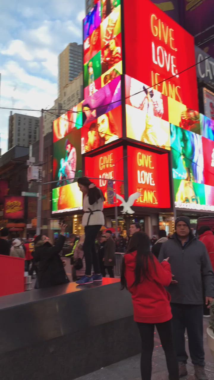 This may contain: people are standing on the sidewalk in front of large billboards that say give love