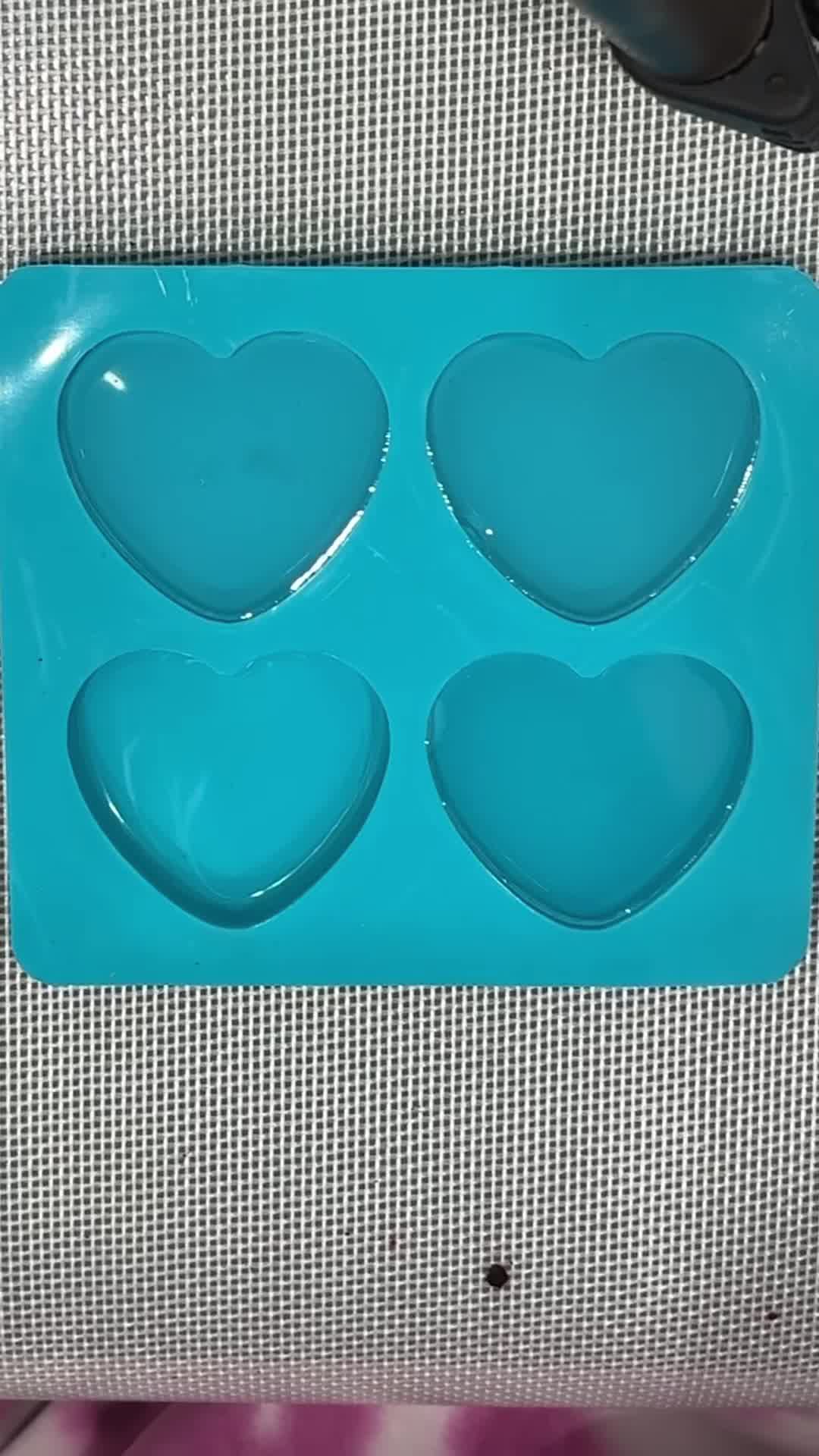 This may contain: a heart shaped glass dish with blue swirls and bubbles in the shape of a heart