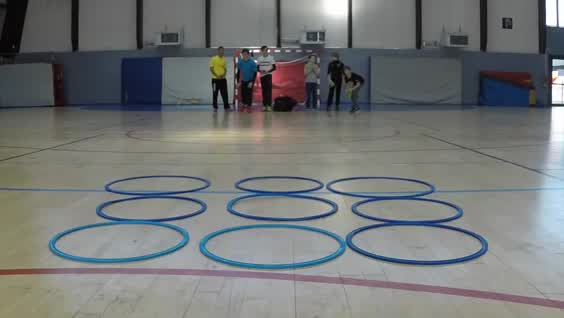 This may contain: a group of people standing on top of a basketball court surrounded by blue hoop rings