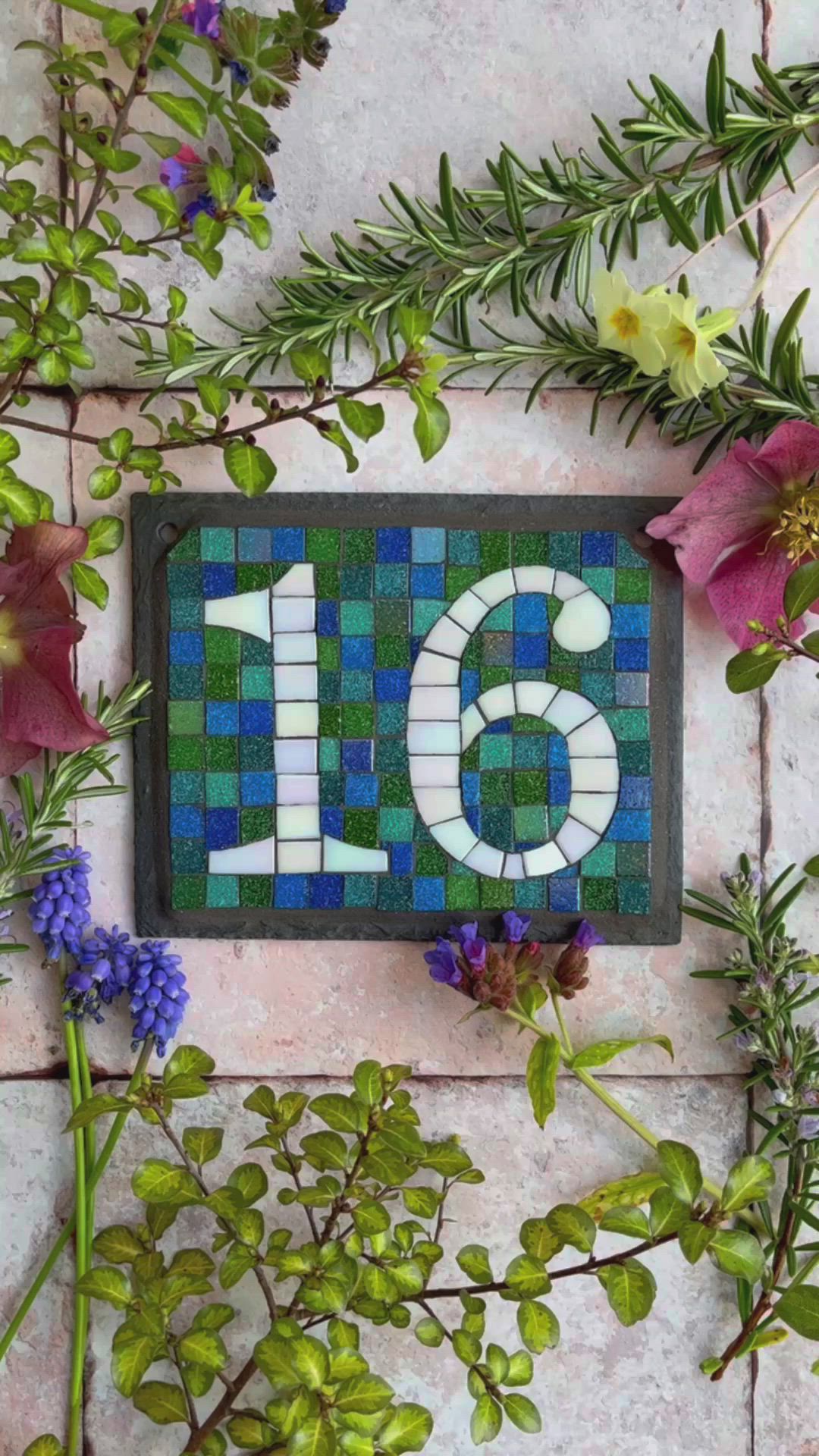 This may contain: two people making letters out of blue and green glass shards on a table with scissors