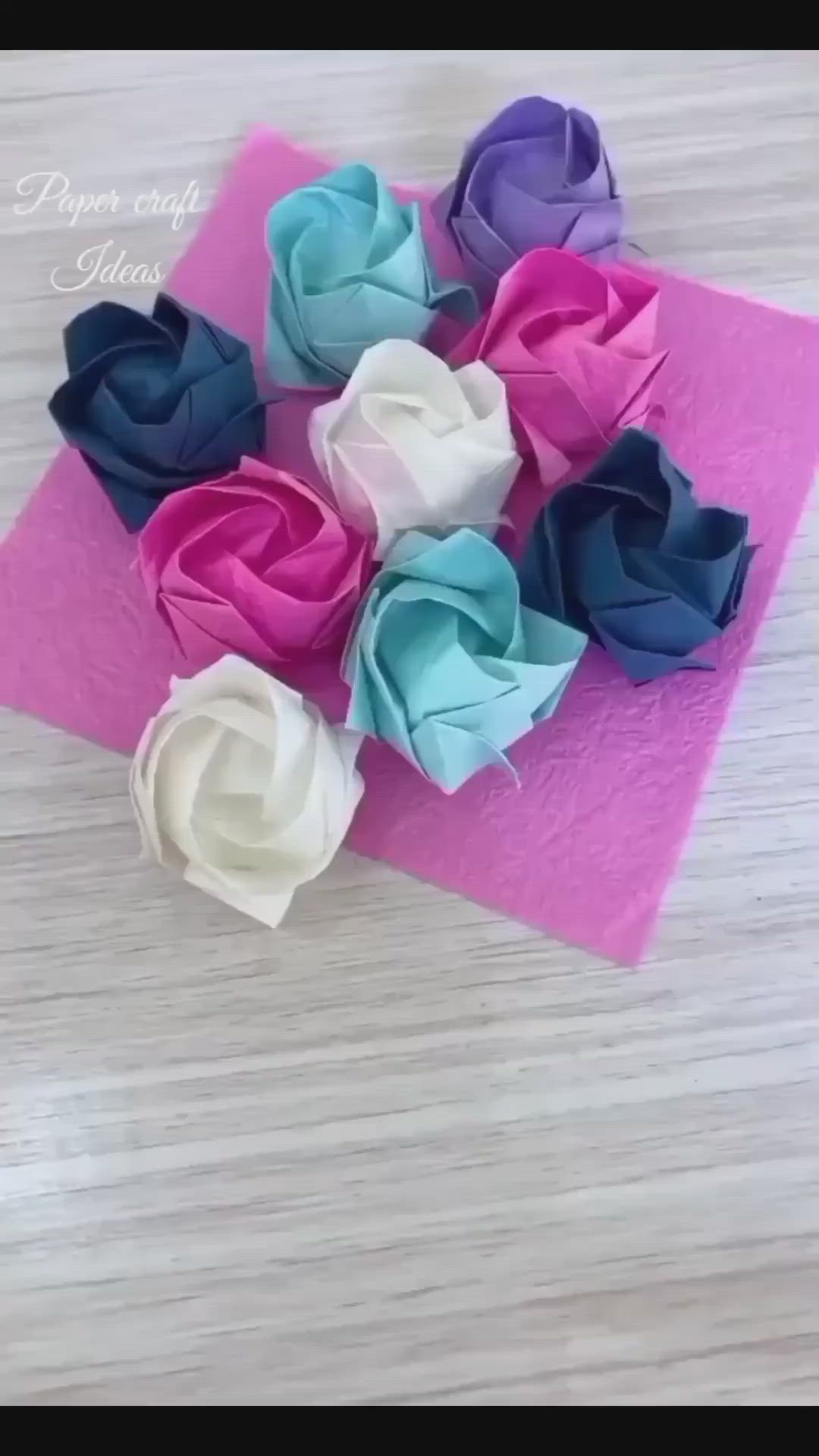 This may contain: several different colored flowers sitting on top of a piece of pink and blue paper,