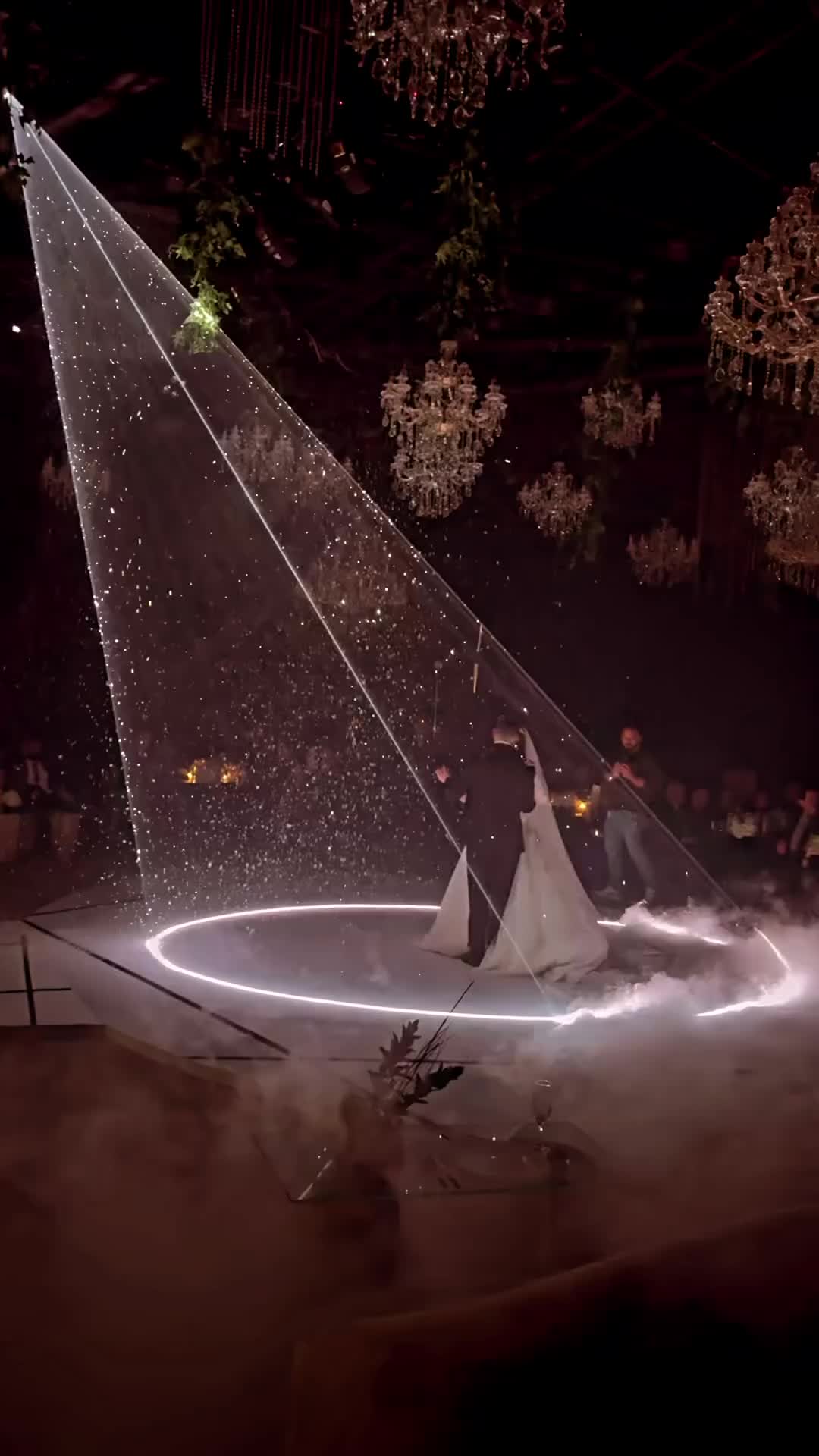 This may contain: a man and woman dancing on a circular stage with lights in the air at night