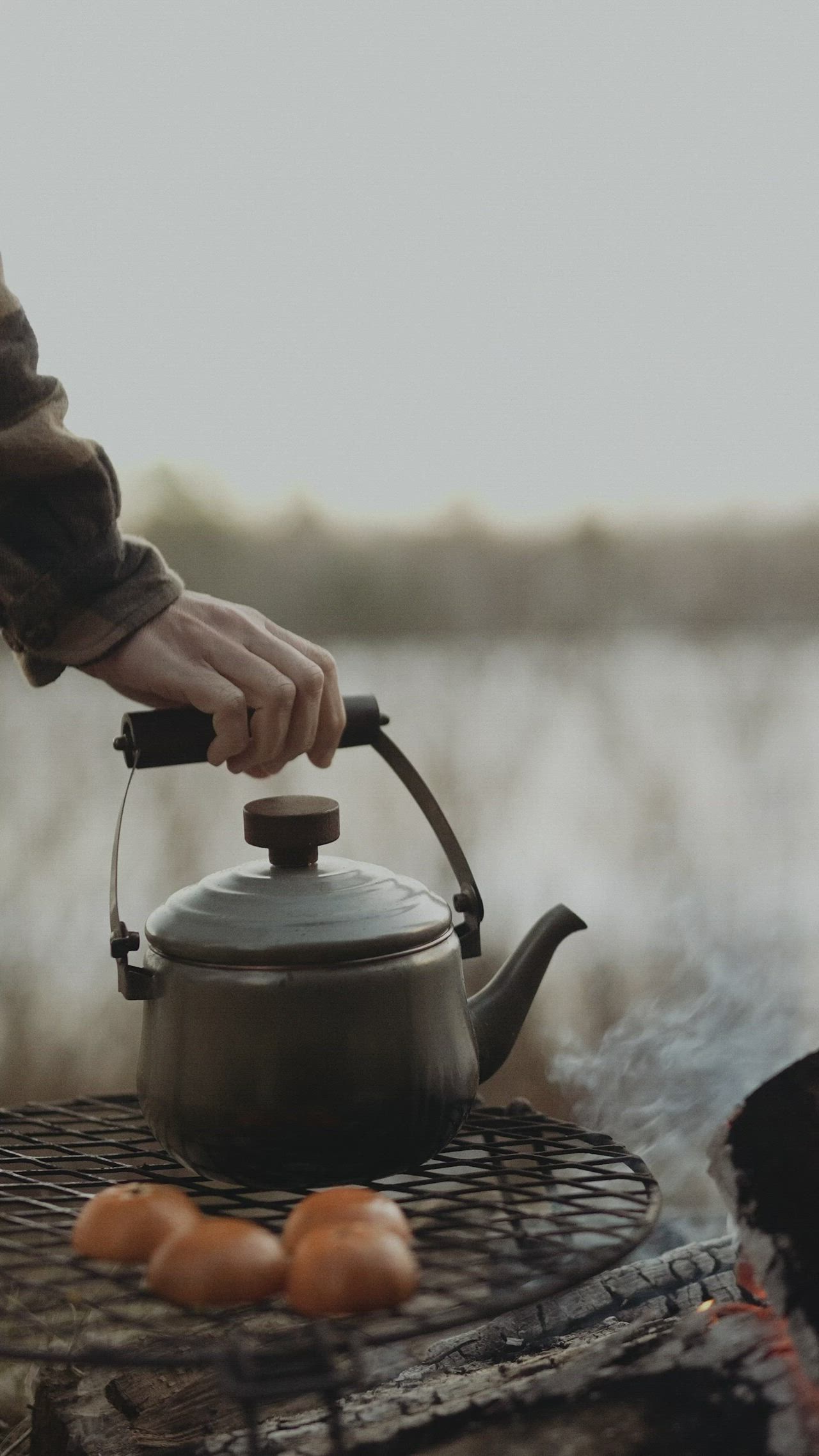 This may contain: a person cooking food on top of a grill with a tea pot and tongs