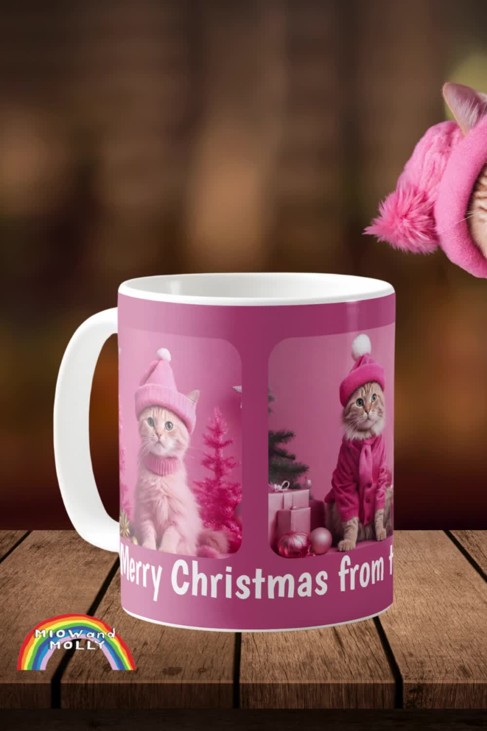 This contains: A pink mug with three different pictures of cats dressed in Pink Winter clothes, in front of Christmas scenes. The mug is also pink.