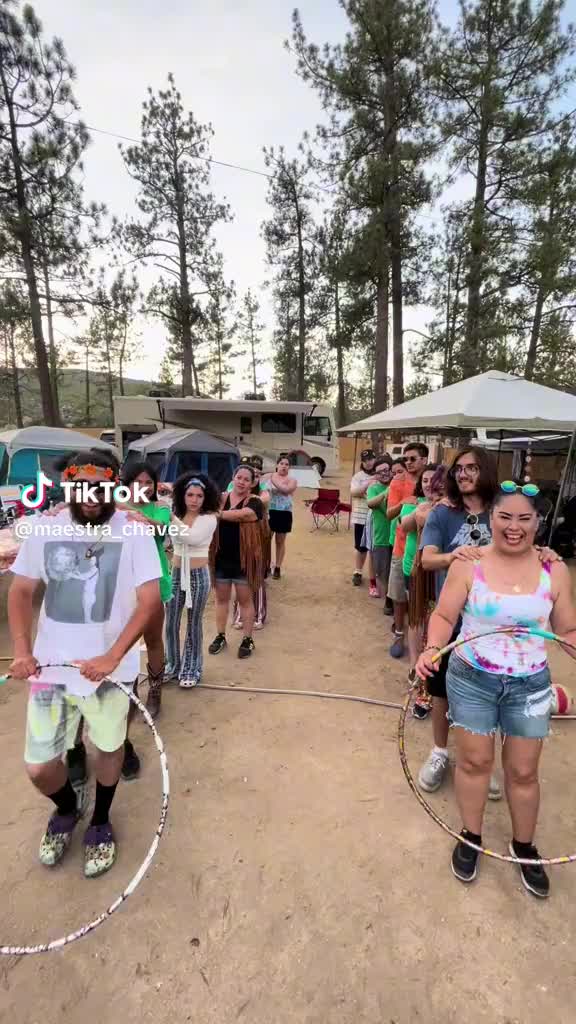 This may contain: a group of people standing on top of a dirt field next to tents and trees