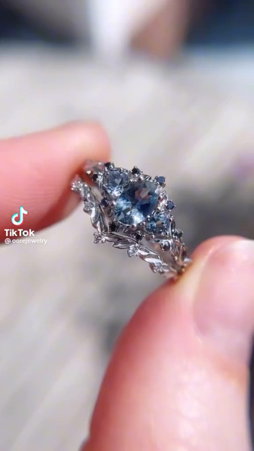 This may contain: a person holding a ring with a blue diamond in it