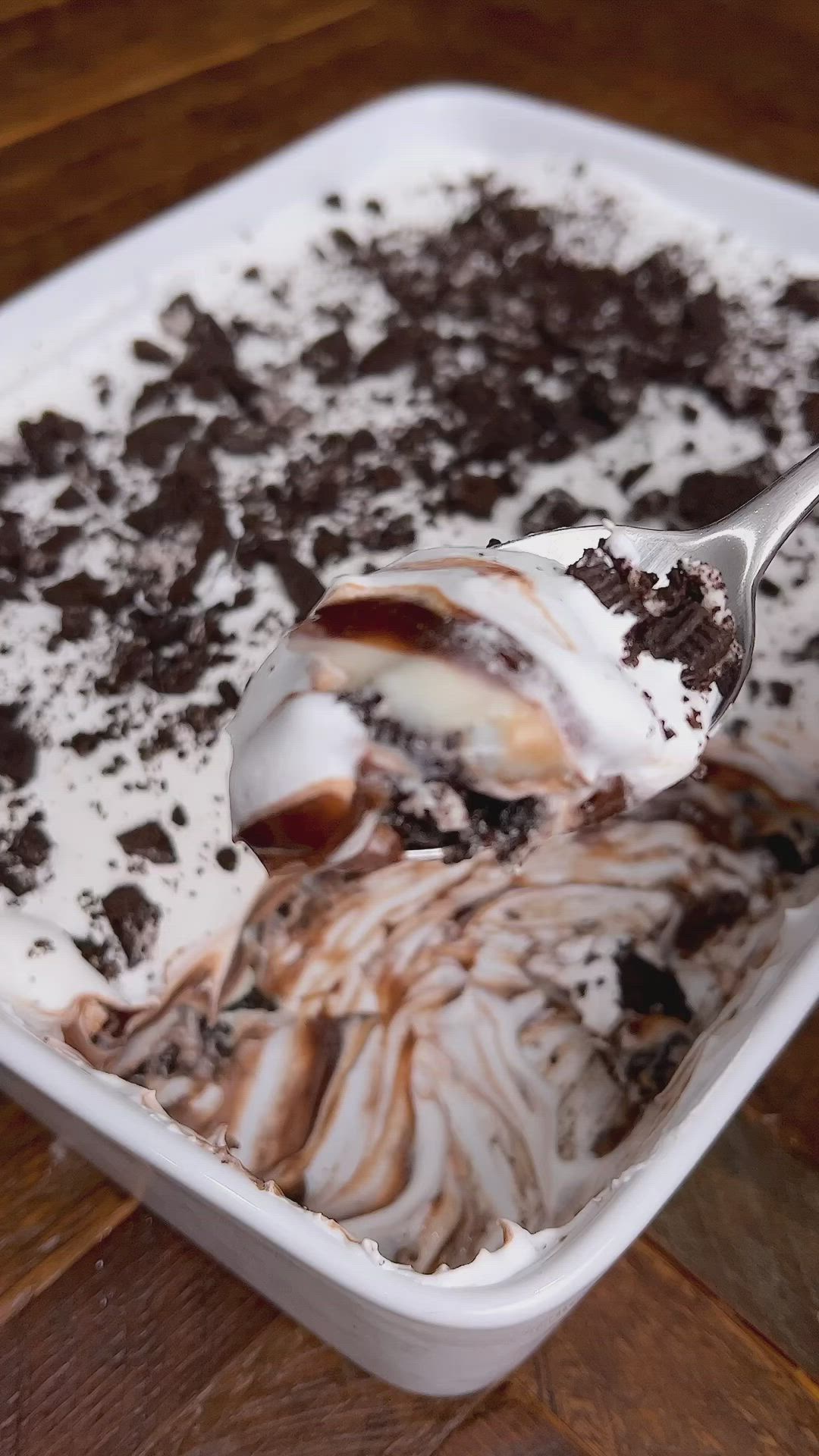 This may contain: an ice cream sundae with chocolate chunks and oreo cookies on top, in a white dish