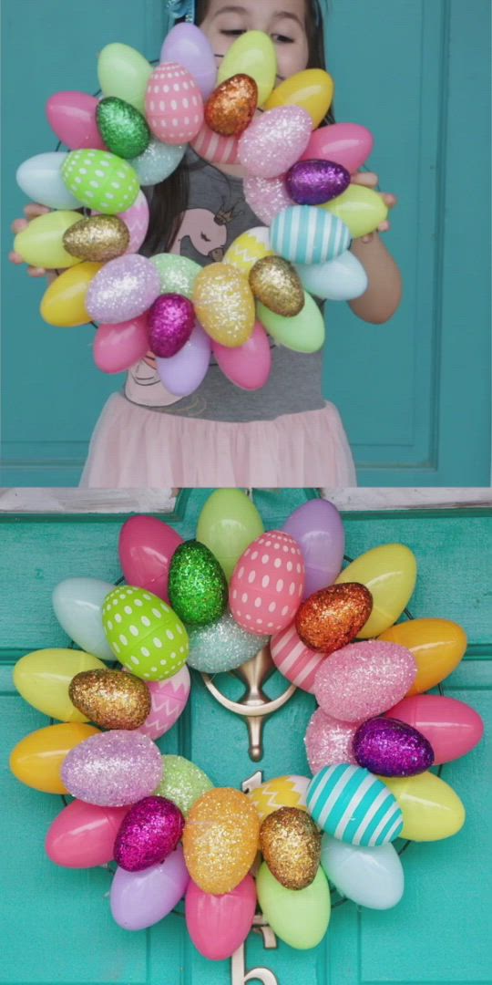 This may contain: an easter wreath made out of balloons and plastic eggs on a blue door with a hand holding scissors