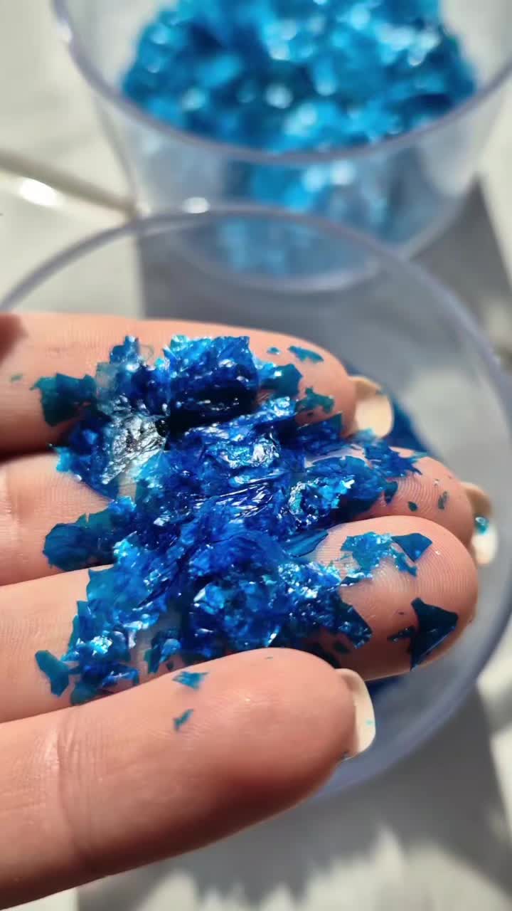 This may contain: someone is holding their hand over some blue powder in a bowl with the words essaberer glitter aus 3 zuuten on it