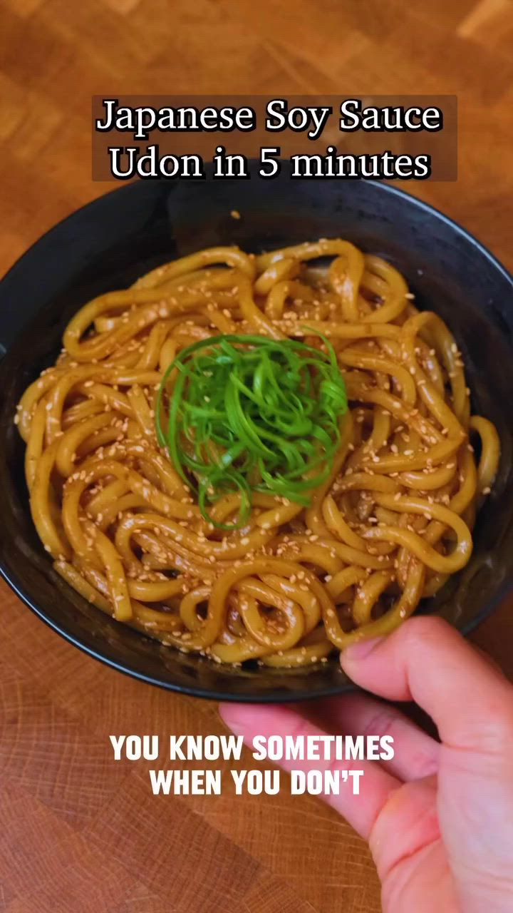 This may contain: someone is holding their hand over a bowl of noodles with the caption japanese soy sauce udon in 5 minutes you know sometimes when you don't