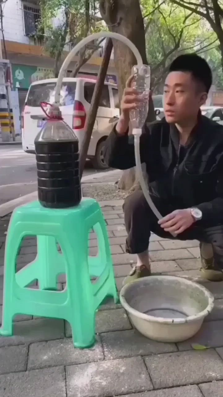 This may contain: a man squatting down next to a water hydrant with a glass in it