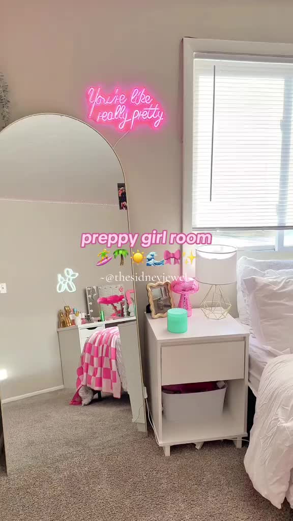 This may contain: a bedroom with a white bed and pink neon sign on the wall next to it