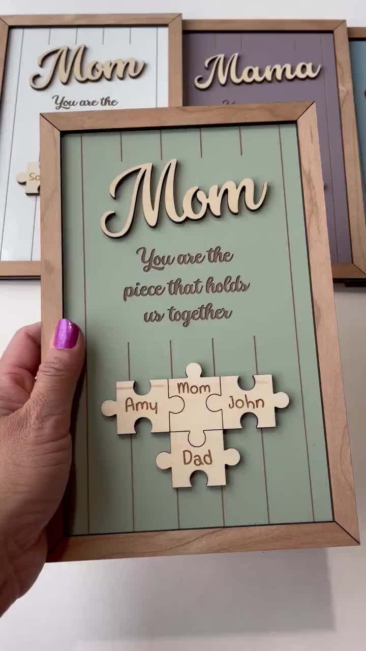 This may contain: a person holding a puzzle piece with the words mom on it and two pieces missing