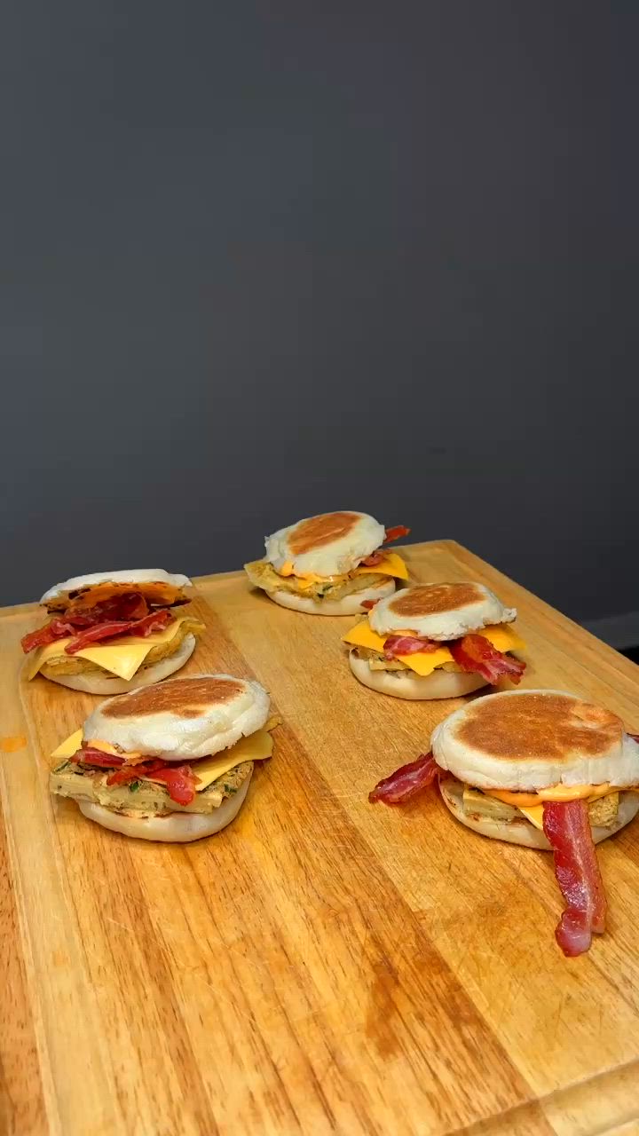 This may contain: a person is holding up a bacon and egg breakfast sandwich on a cutting board with the words healthy breakfast sanwich low - cal, high protein