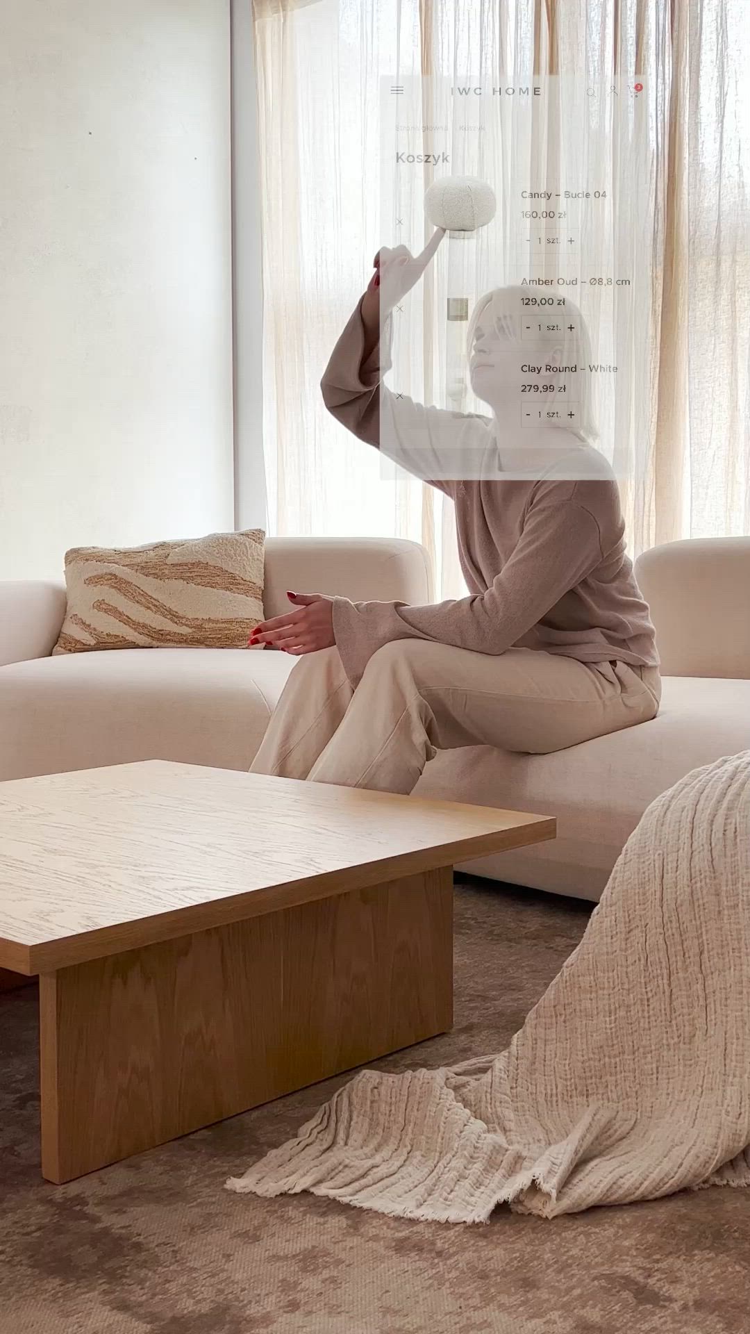 This may contain: a woman sitting on top of a couch next to a coffee table in front of a window