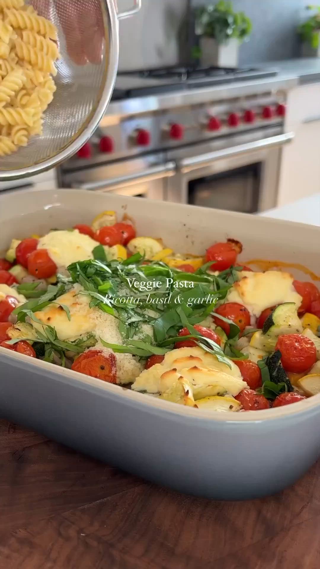 This may contain: a casserole dish with tomatoes, spinach and pasta in it on a wooden table