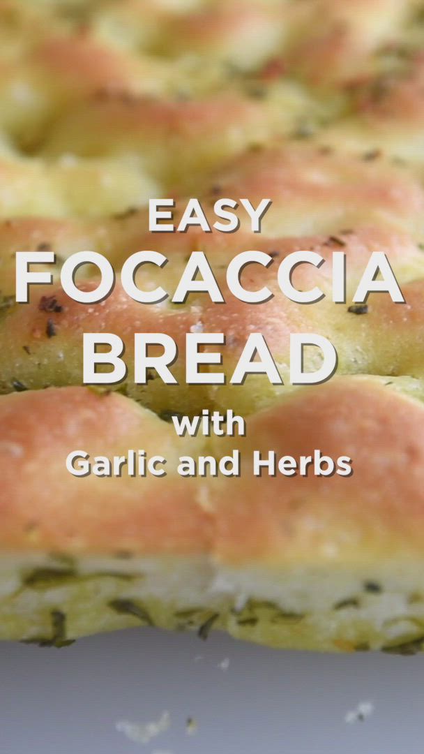 This may contain: someone is holding up some bread with garlic and herbs on it in front of the words easy focaccia bread