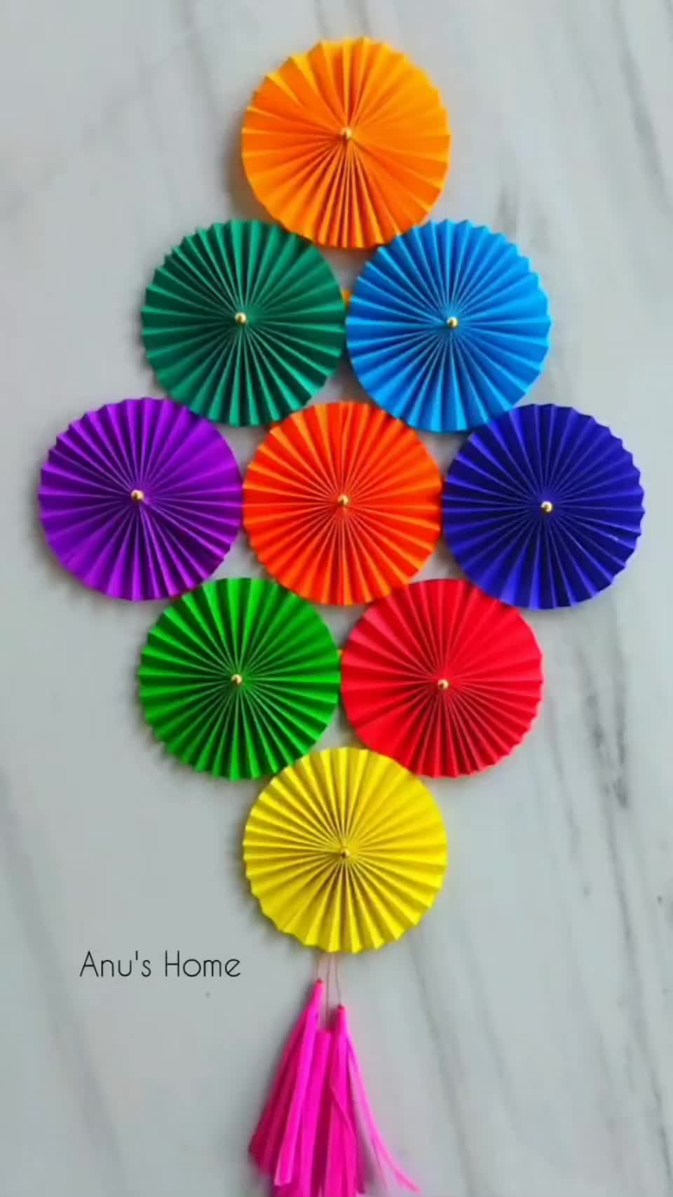 This may contain: colorful paper fans with tassels hanging from the side on a marble countertop