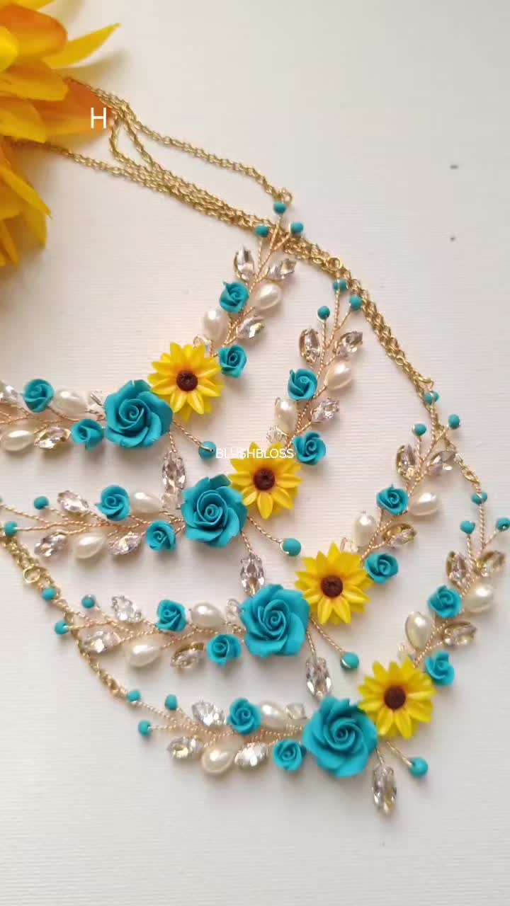 This may contain: a necklace with sunflowers and blue flowers on it next to a yellow flower