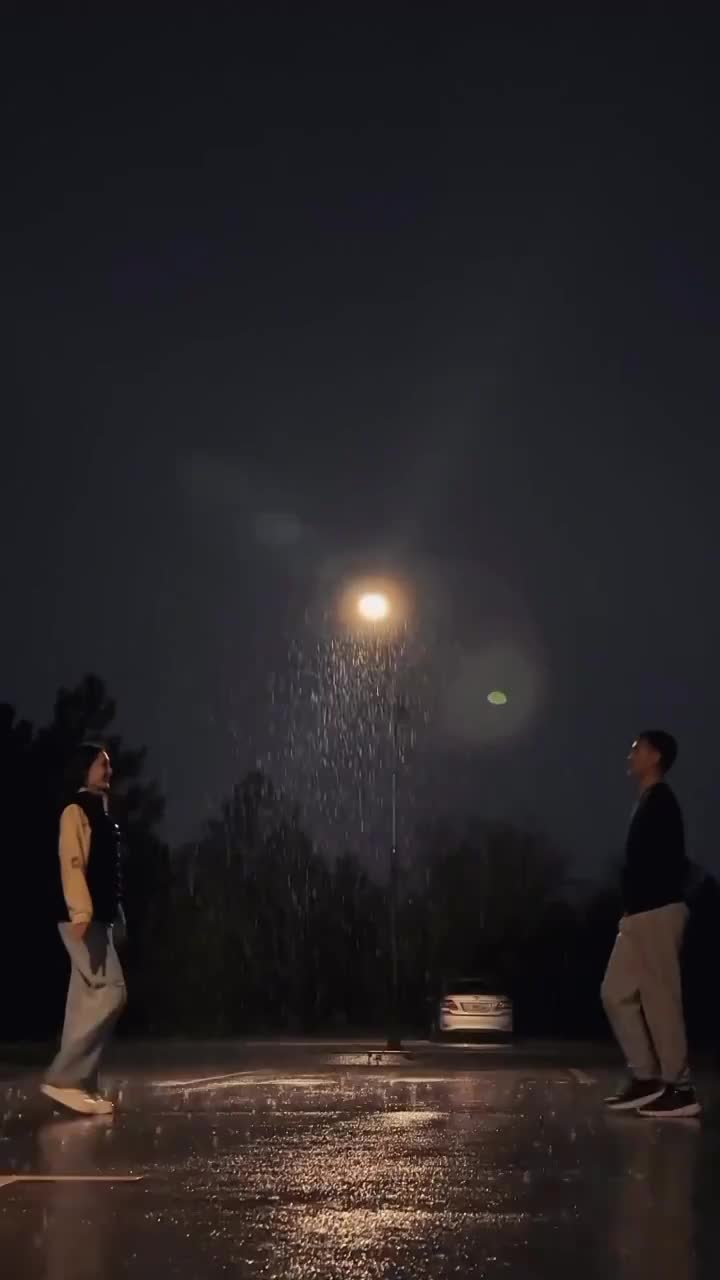 This may contain: two people are walking in the rain at night