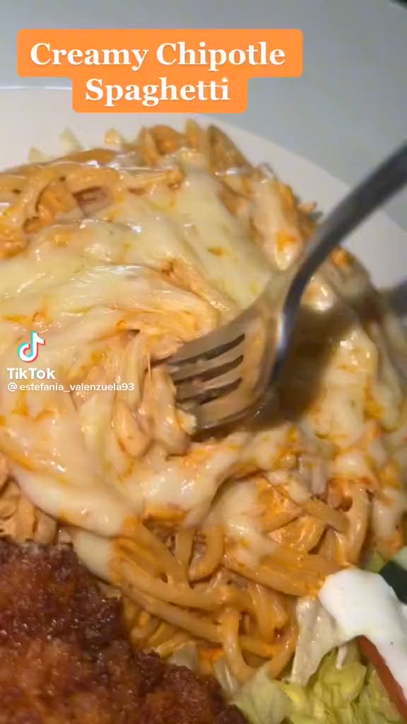 This may contain: a white plate topped with pasta covered in cheese and sauce next to a fork on top of it