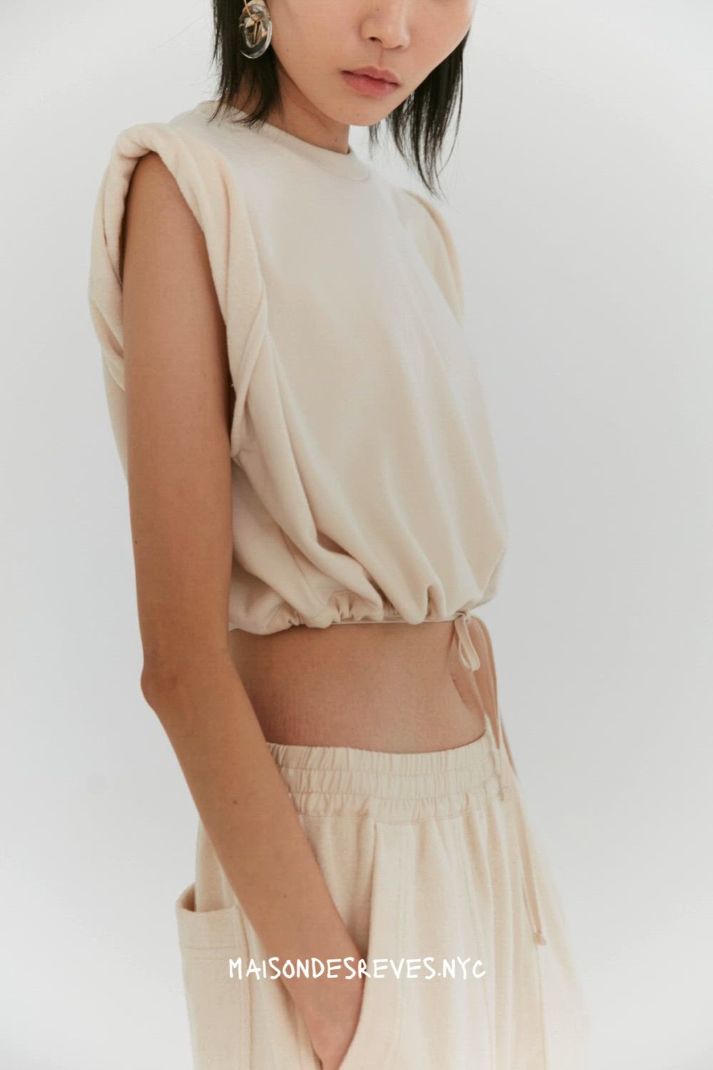 This slightly cropped sleeveless top features a boxy silhouette and a rolled shoulder detail. Trimmed with a tencel drawstring, this top can be worn relaxed or synched at the waist to create a shorter blouson shape. Made in our terry looped cotton jersey and finished with a ribbed crew neck, the front is discreetly branded with our tonal monogram embroidery. #fashionessentials #casualchic #wardrobestaple #versatilestyle #rolledsleevetop #ootdinspiration #fashionforward #everydayelegance