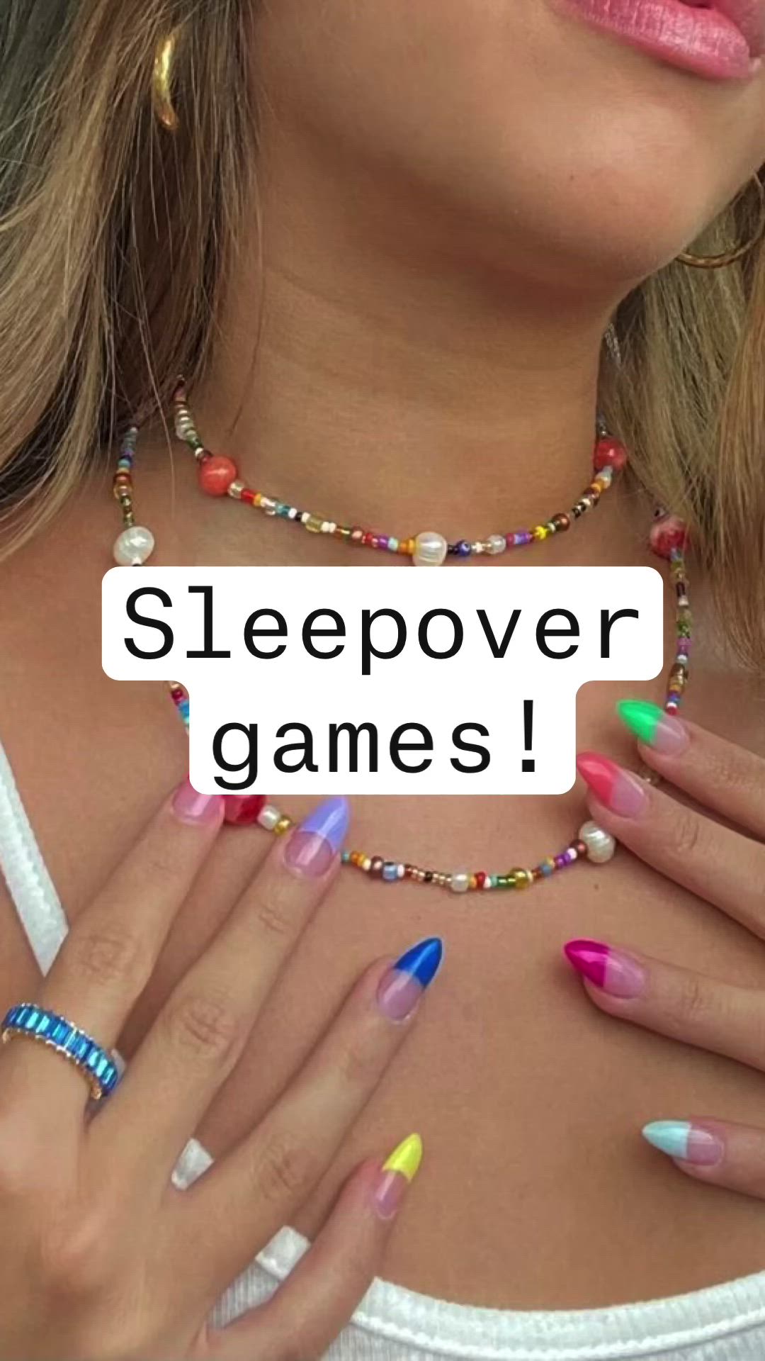 This may contain: a woman with colorful nails holding a sign that says sleepover games on her chest