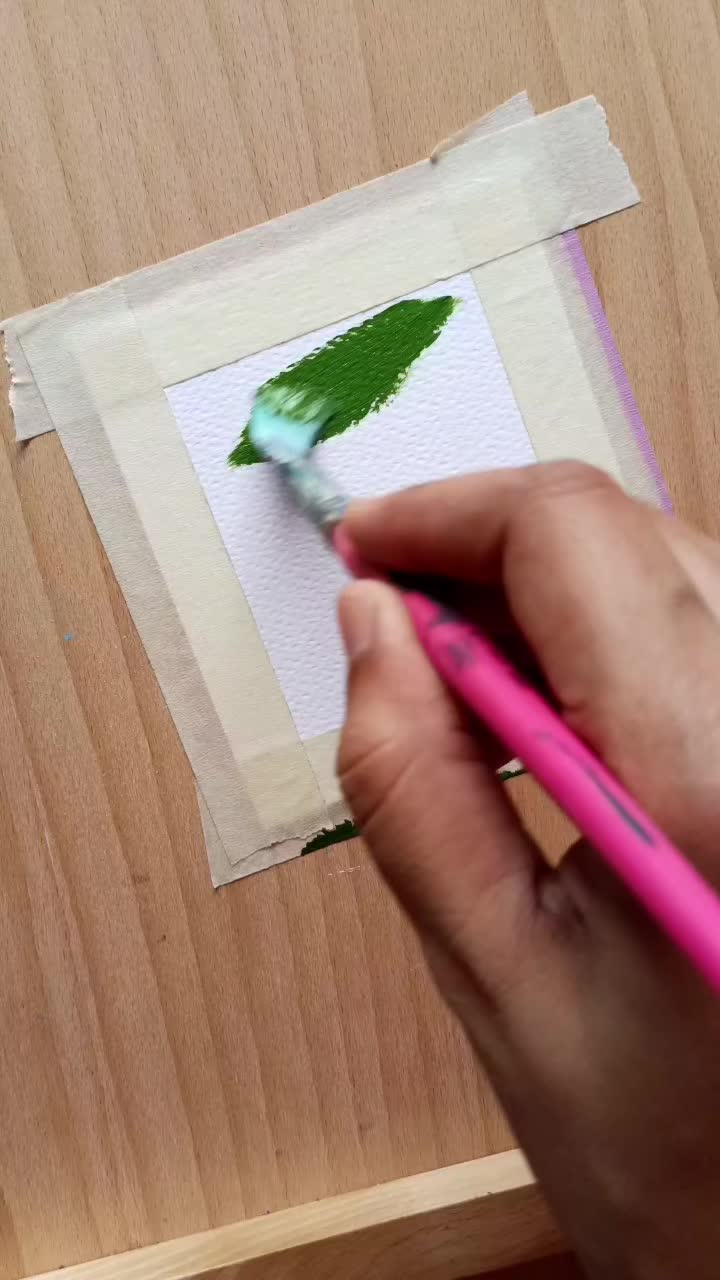 This may contain: someone is using scissors to cut the paper with white flowers on green square in center