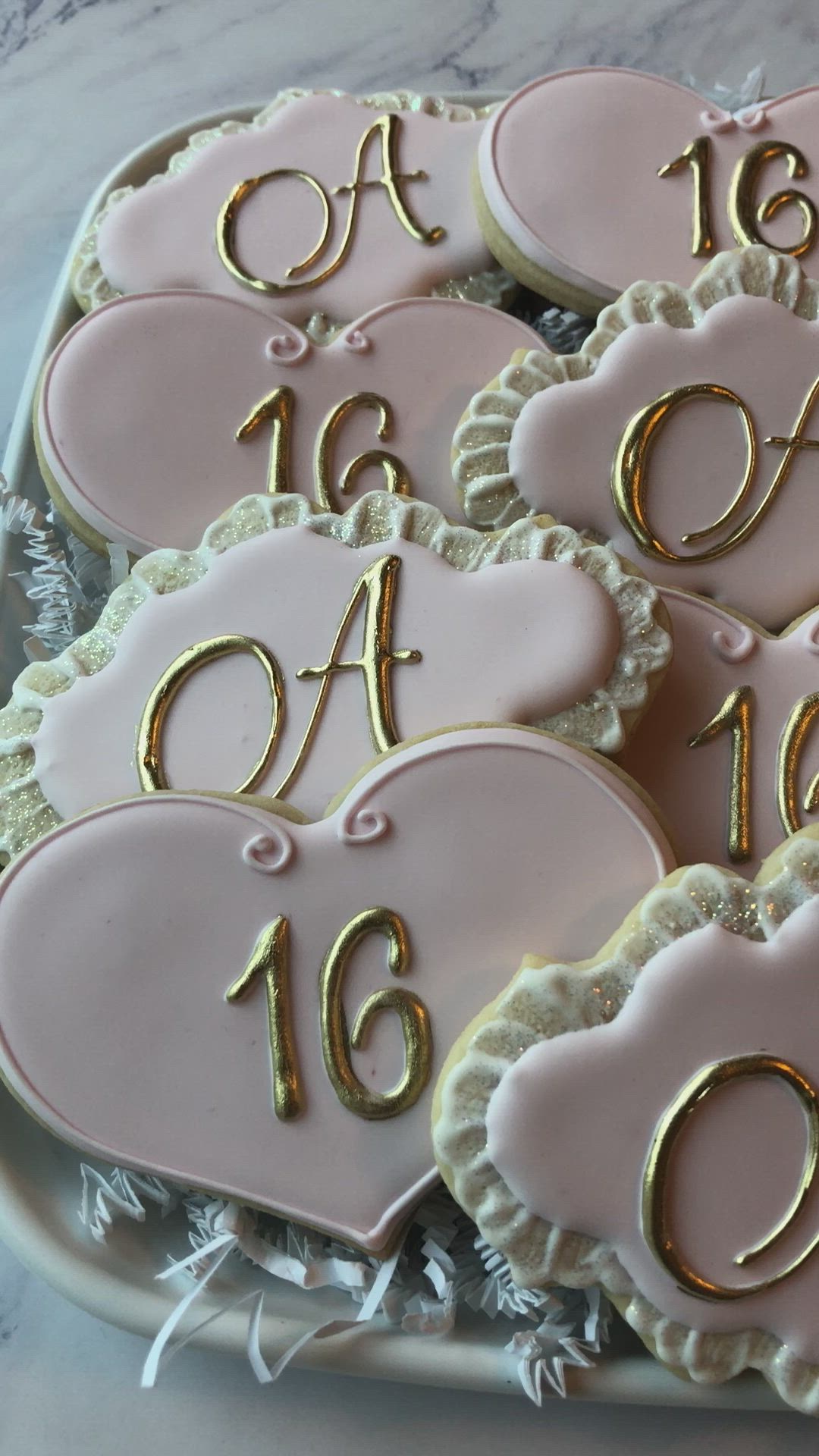 This may contain: decorated cookies in the shape of hearts with gold letters and numbers on them are displayed