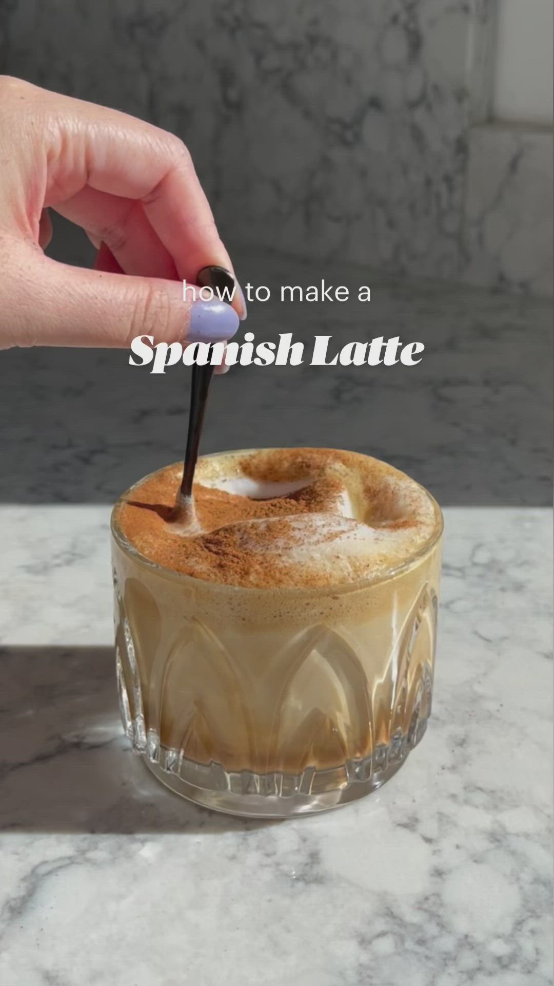 This may contain: someone is holding a spoon over a drink in a glass with the words, how to make a spanish latte