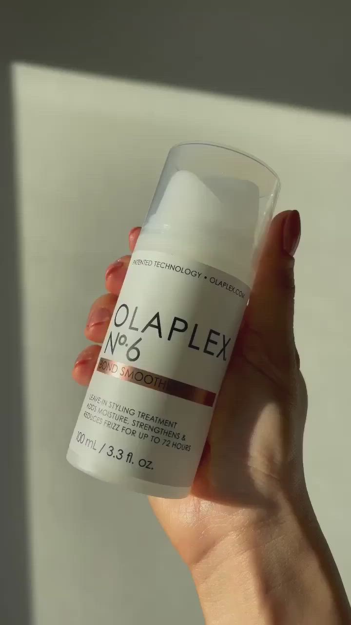 This contains: A model showcasing how she uses OLAPLEX N°.6 with the new air-less pump to style her hair