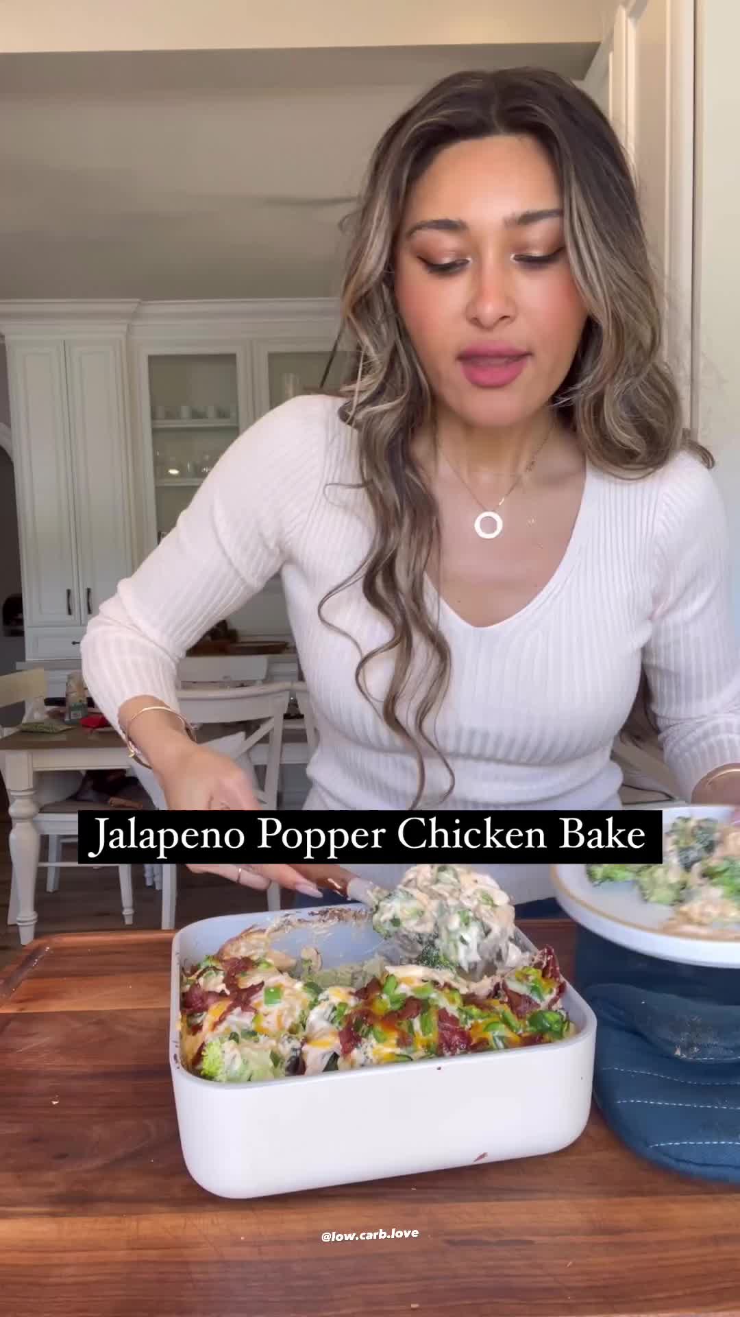 This may contain: a woman holding up a plate with food on it and the words jalapeno popper chicken bake