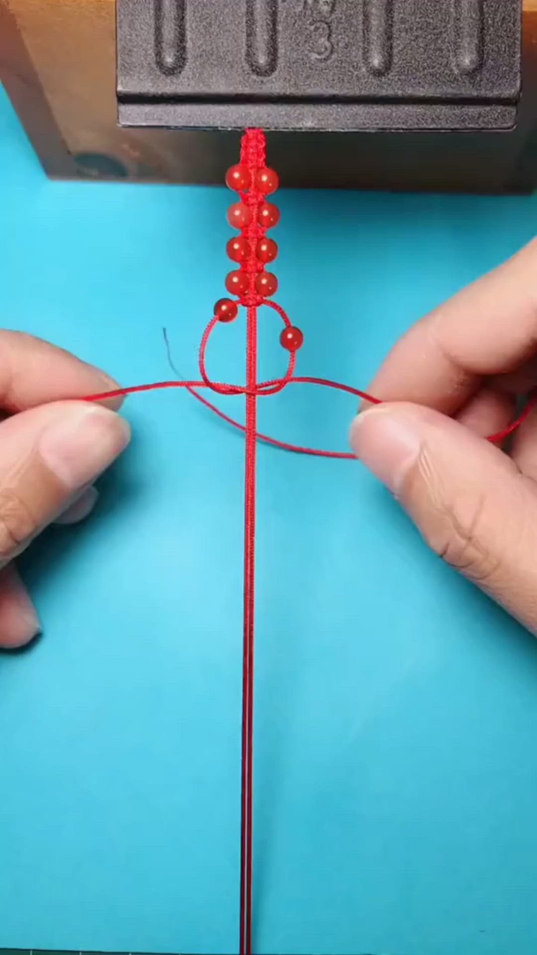 This may contain: two hands are working on an object with red thread