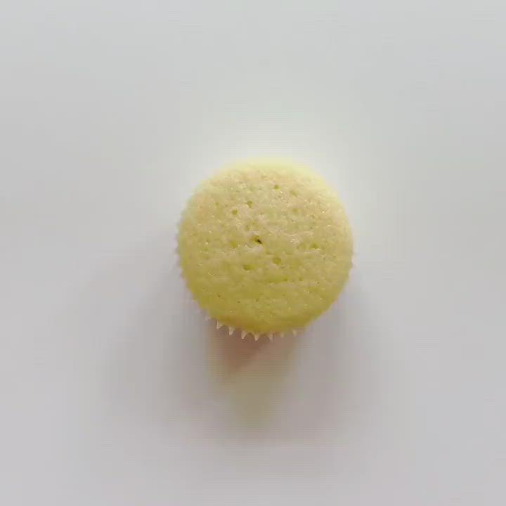 This may contain: a yellow cupcake sitting on top of a white table