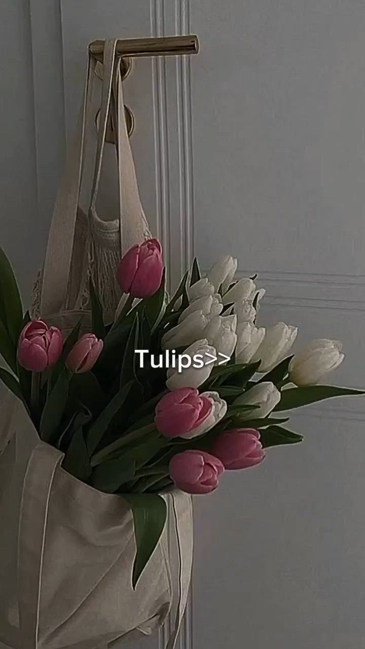 This may contain: a white bag with pink and white tulips hanging from it's side