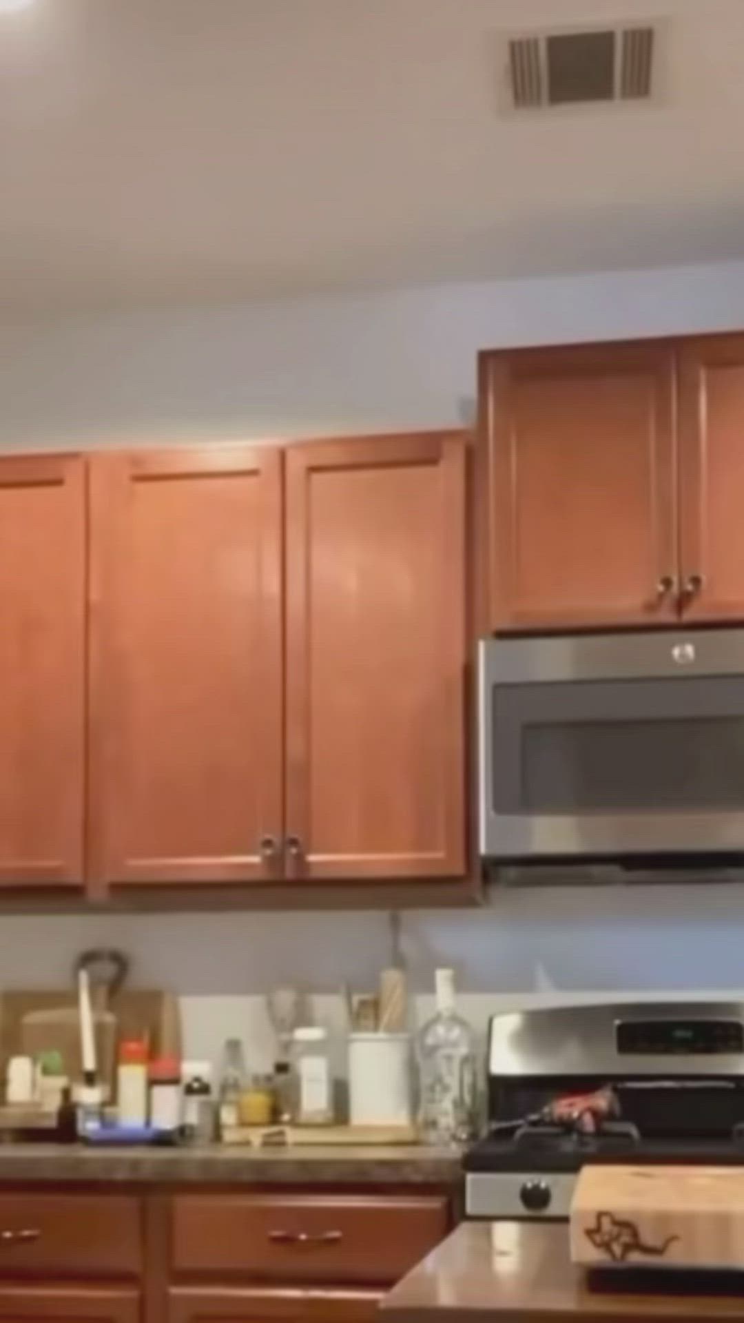 This may contain: a kitchen with wooden cabinets and stainless steel microwave above the stove, is seen in this image