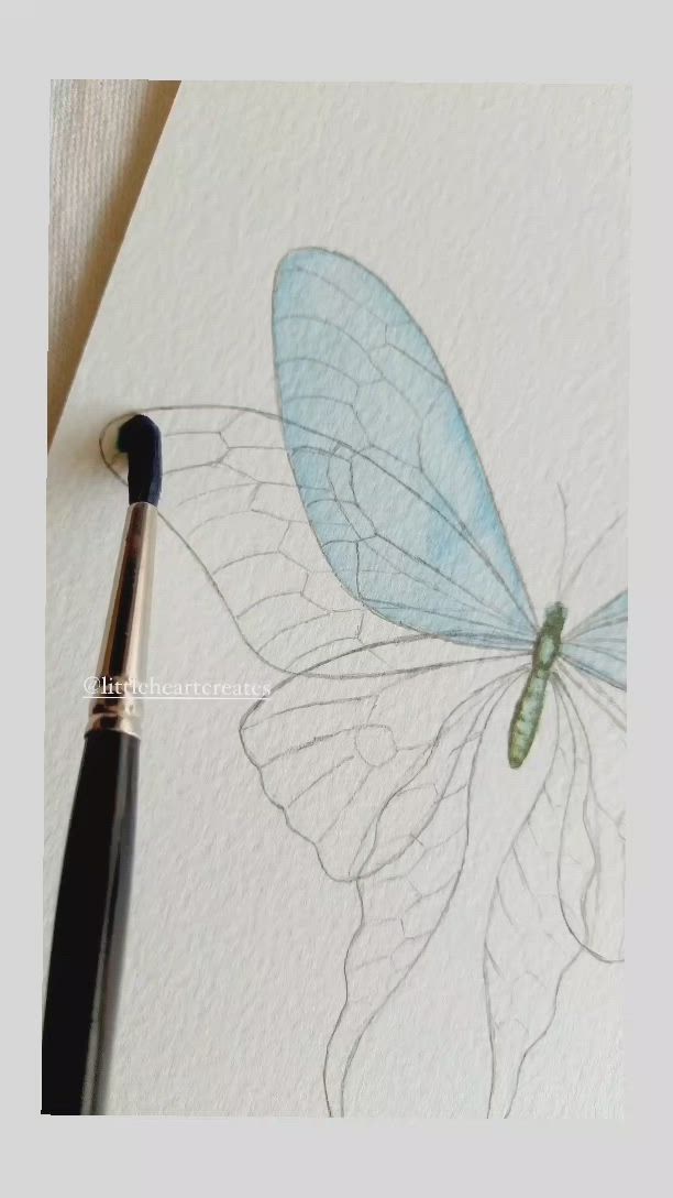 This may contain: a drawing of a blue dragonfly on white paper with a black ink pen next to it