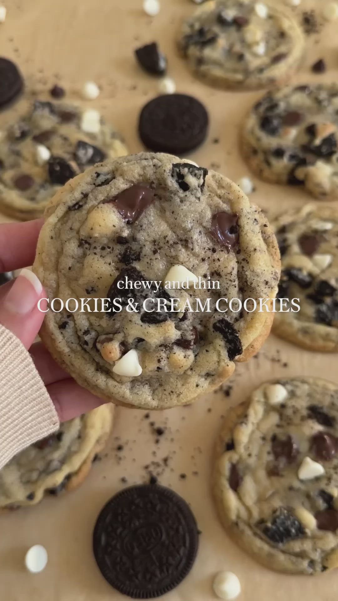 This may contain: a hand holding an oreo cookie with chocolate chips and marshmallows on it