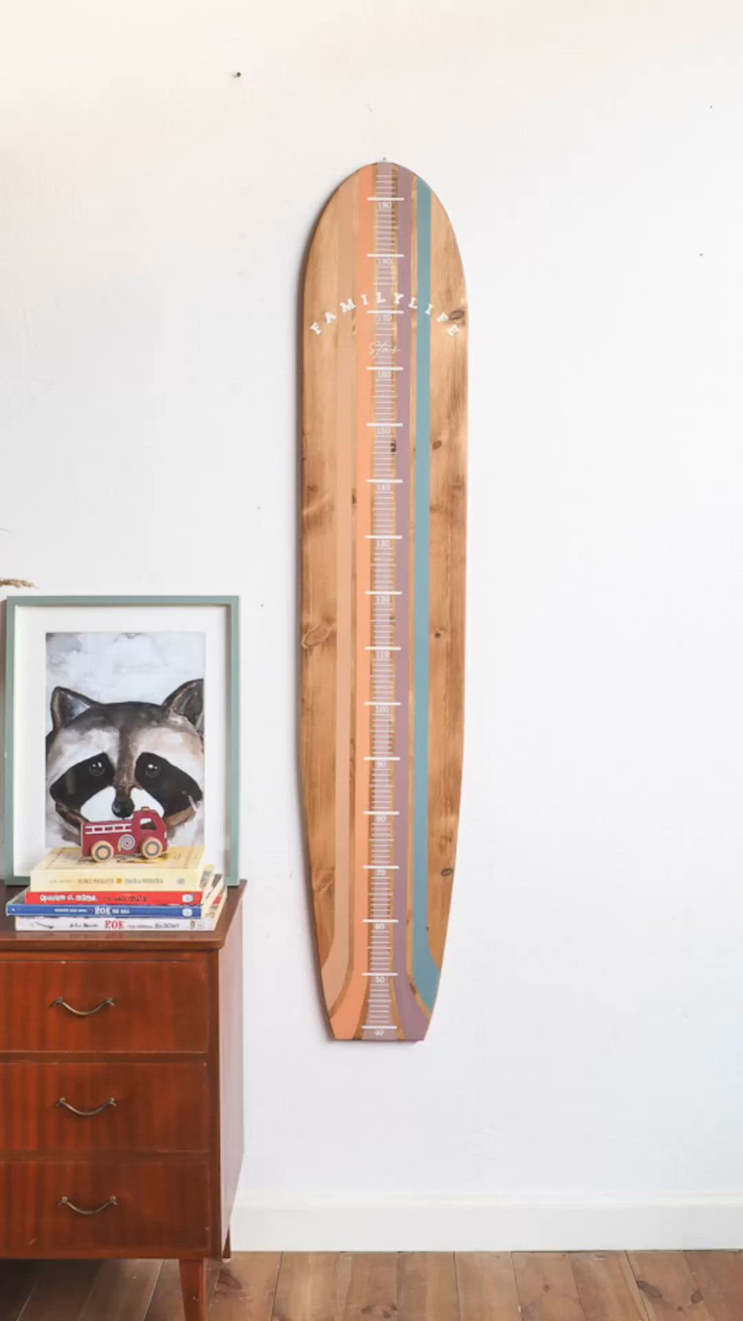 This may contain: a wooden surfboard mounted on the wall next to a dresser with books and pictures