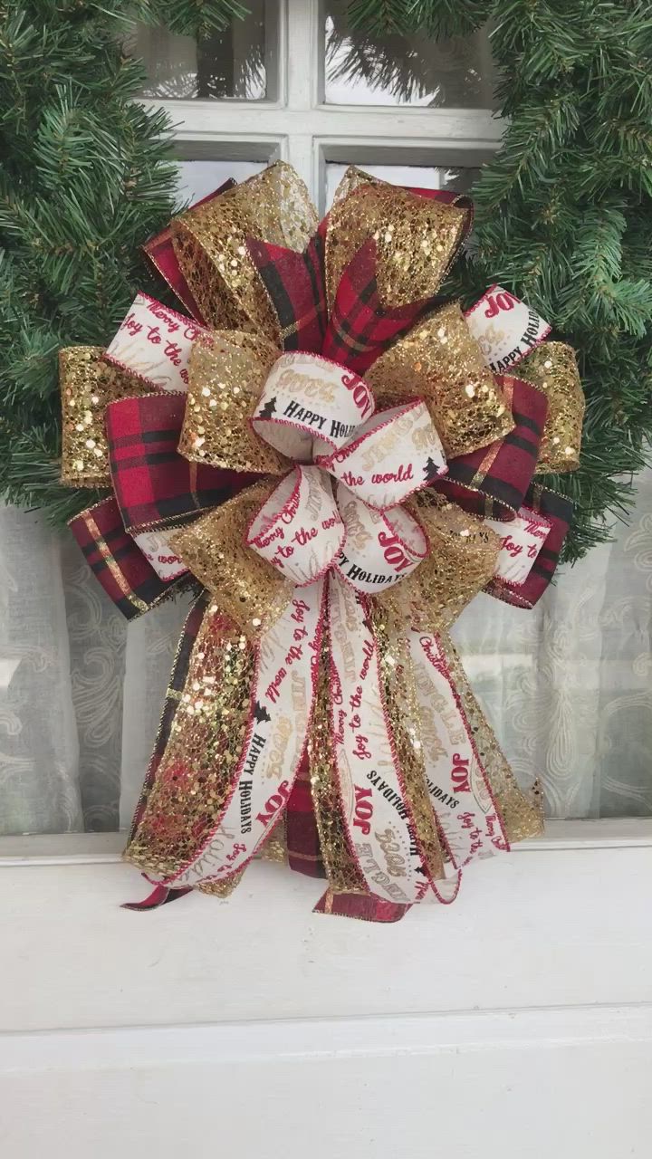 This may contain: a red and gold christmas wreath sitting on top of a window sill