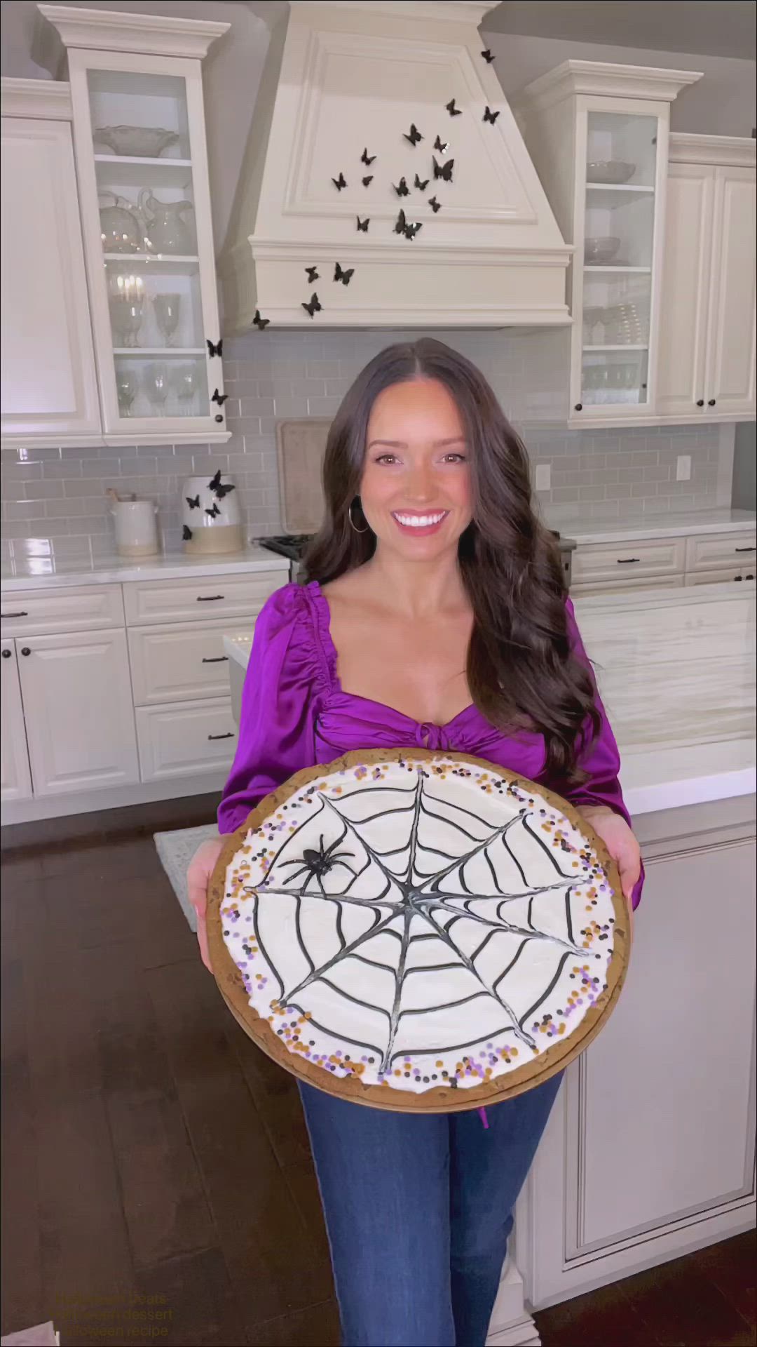 This may contain: a woman holding up a cake decorated like a spider web