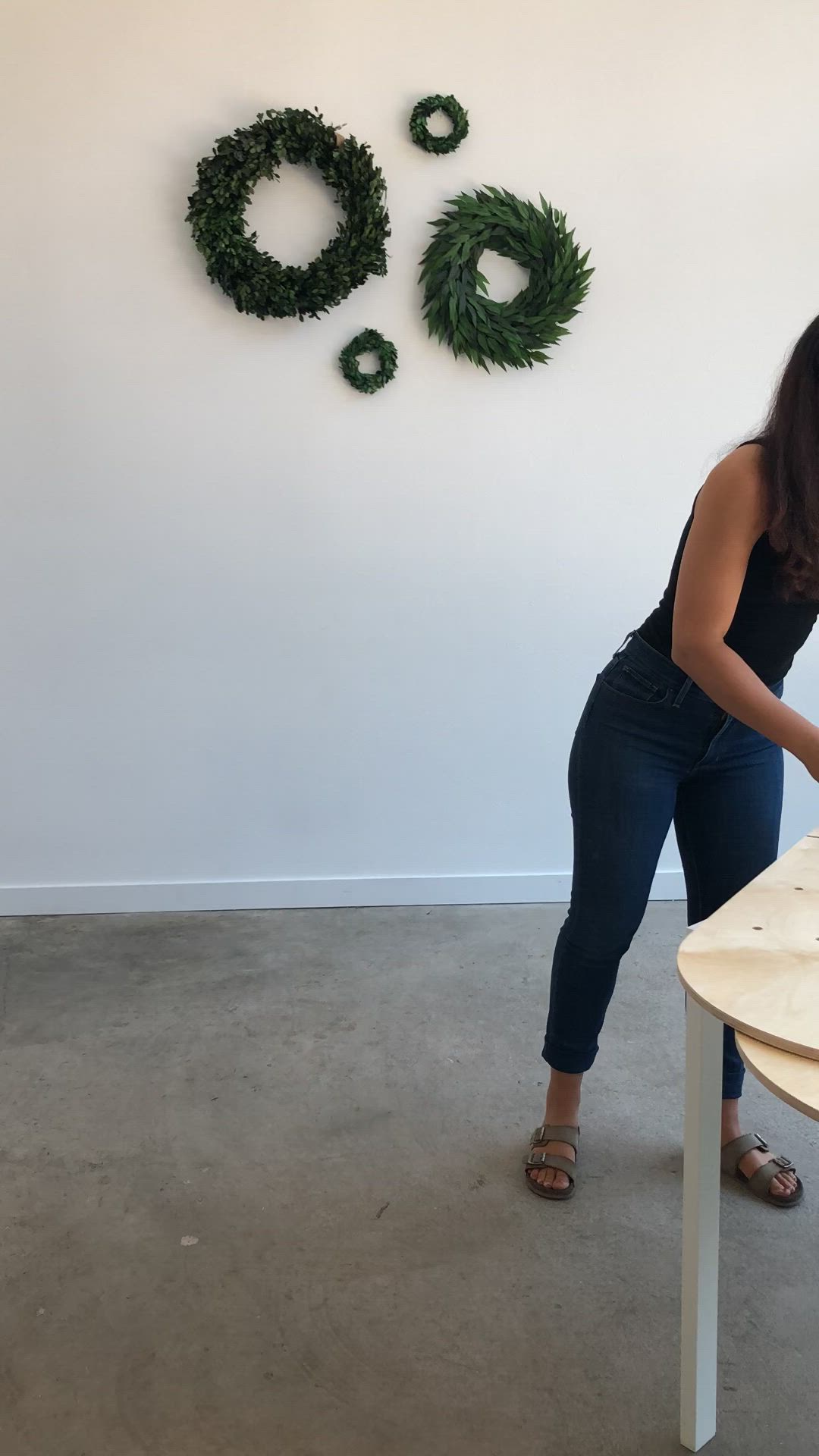 This may contain: a woman standing in front of a wooden sculpture with wreaths on the wall behind her