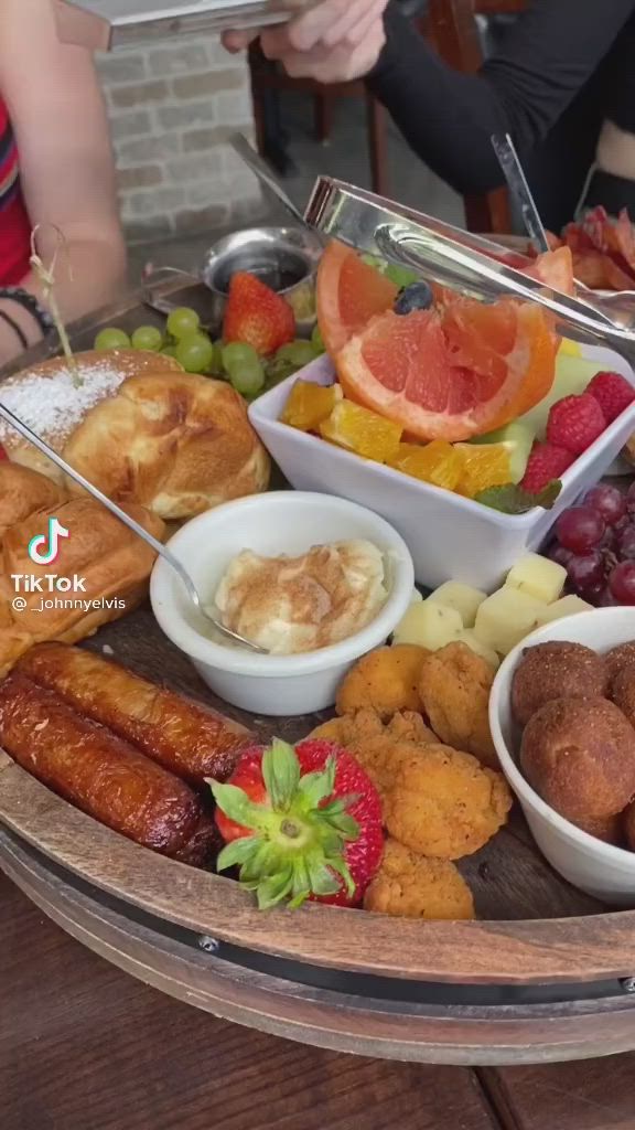 This may contain: a platter filled with different types of fruit and pastries on top of a wooden table