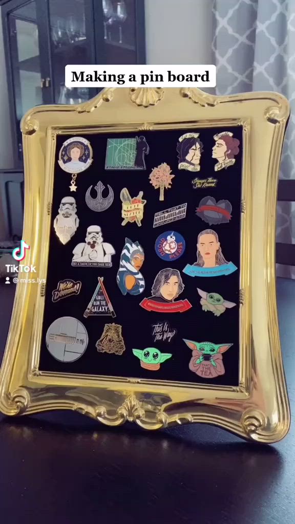 This may contain: the star wars pin collection is displayed in a gold frame on top of a table