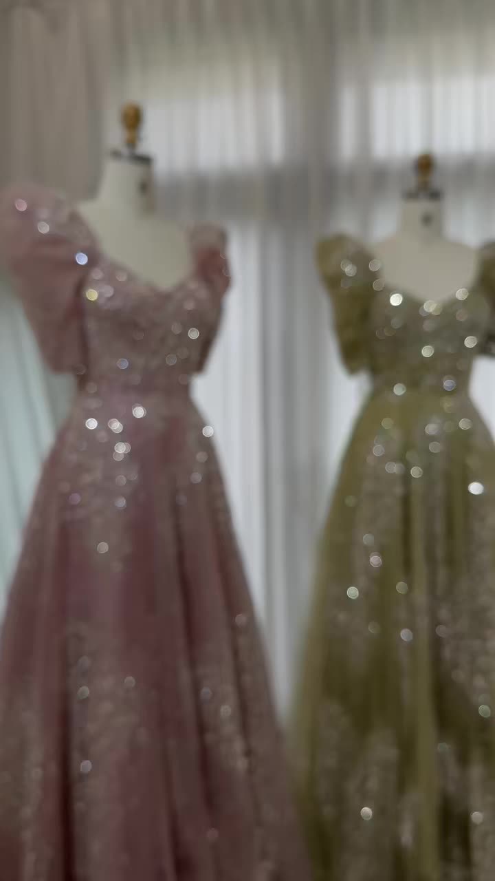 This may contain: two dresses on mannequins in front of a window with curtains behind them